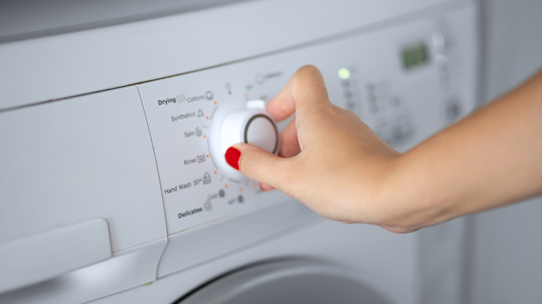 Woman setting program for washing machine.