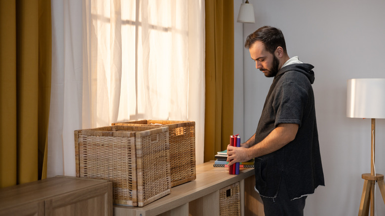 Man organizing items on wooden credenza