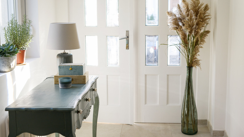A modern home entryway with forest green console table, lamp, and plants