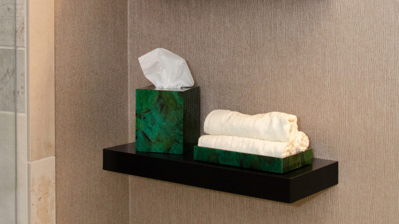 Decorative floating shelves in bathroom styled with various decor pieces