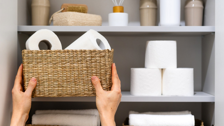Person placing storage container on bathroom shelf