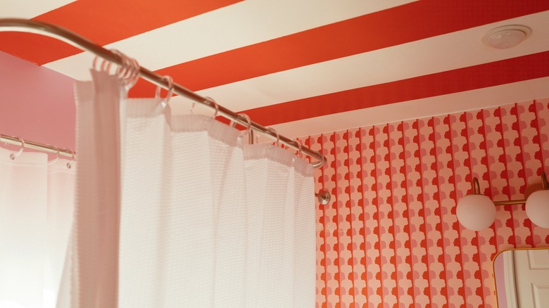 Bathroom with red and white striped ceiling and patterned red and white wallpaper.