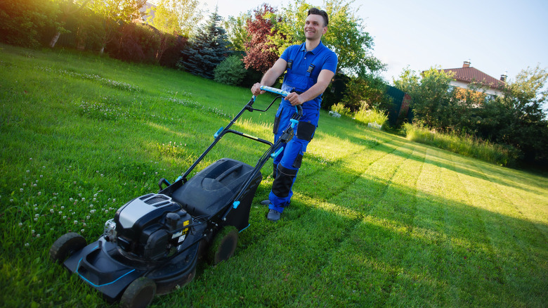 Man mowing a yard mixed with sun and shade