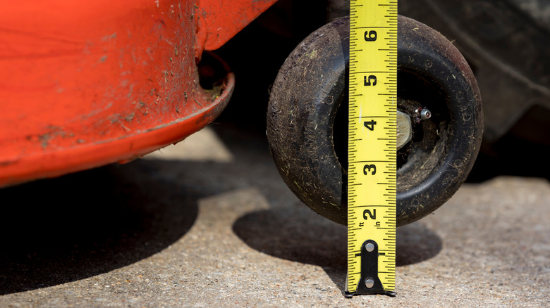 Person measuring the height of a mower deck