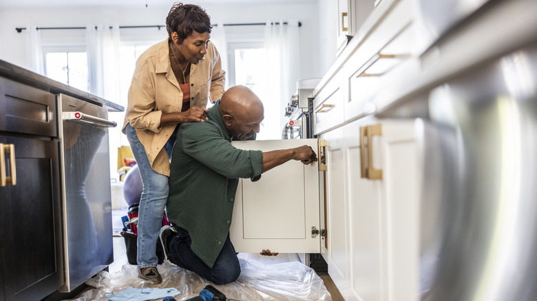 A couple in the kitchen installing new cabinet hardware