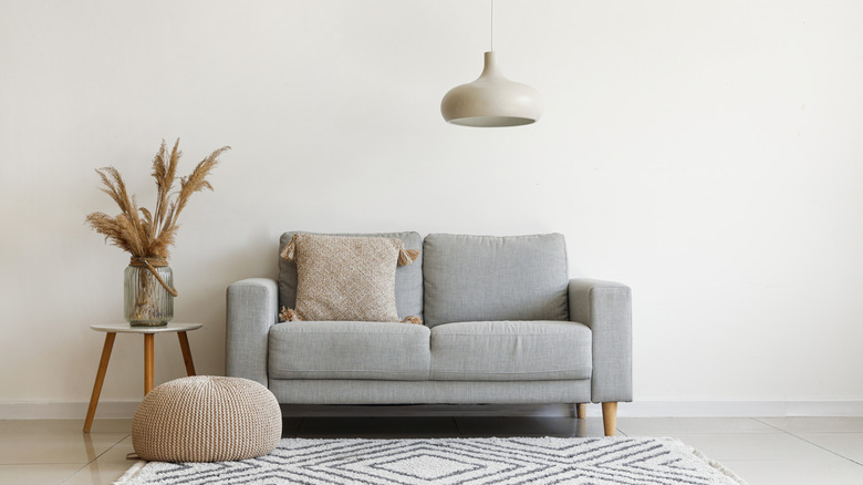 vase filled with dried pampas grass on a side table next to a couch