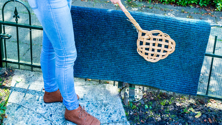 person beating a doormat