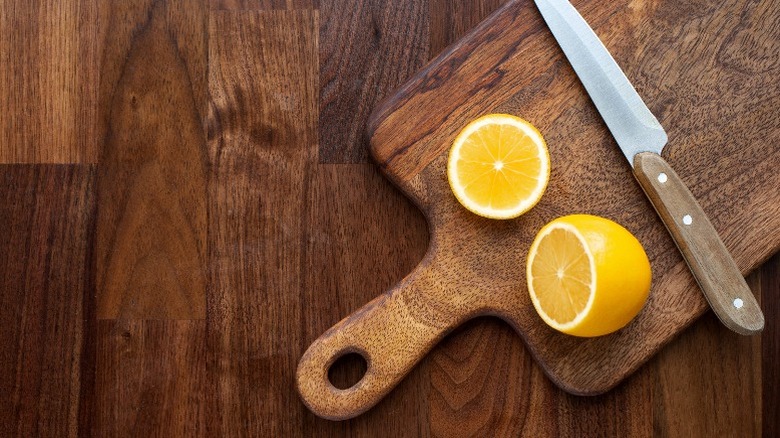 halved lemon and knife on wood cutting board