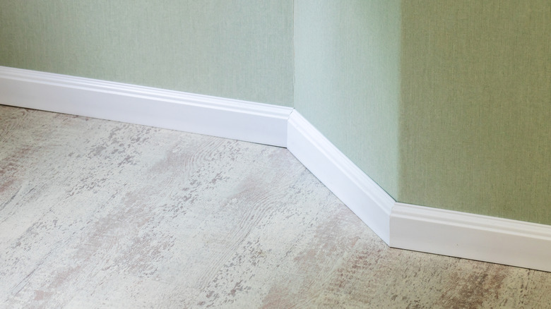 White baseboards in a room with green walls