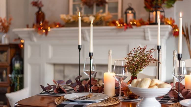 Taper candles and pillar candles lit on a Thanksgiving dining table