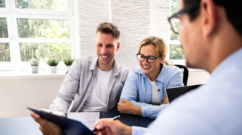 A man and a woman sit across from a financial advisor, smiling