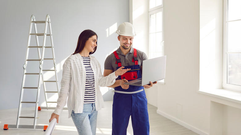A woman stands next to a male contractor, discussing renovation plans