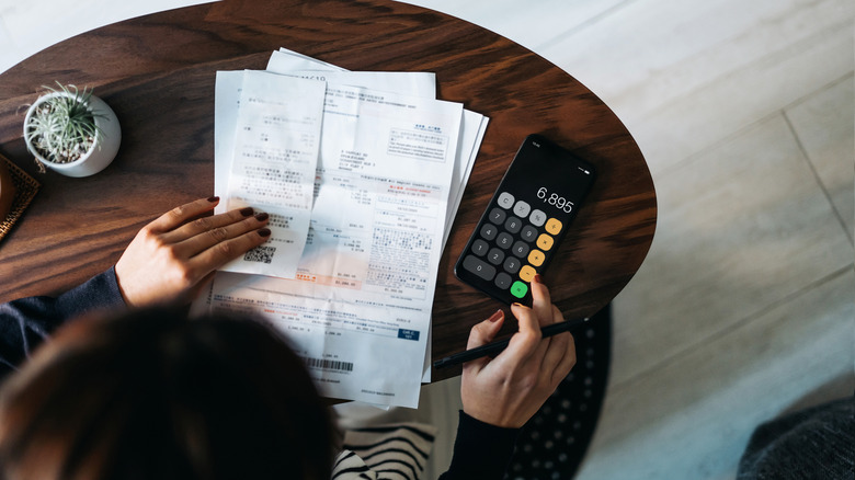 Overhead view of a woman going through papers with a phone calculator