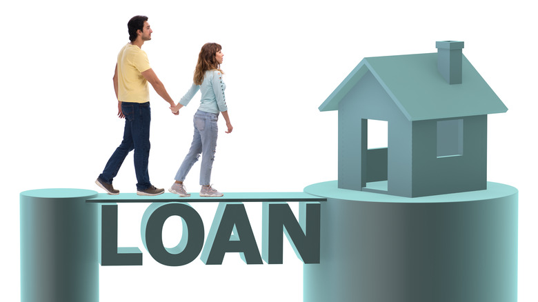 A woman and man symbolically walking across the word loan toward a house