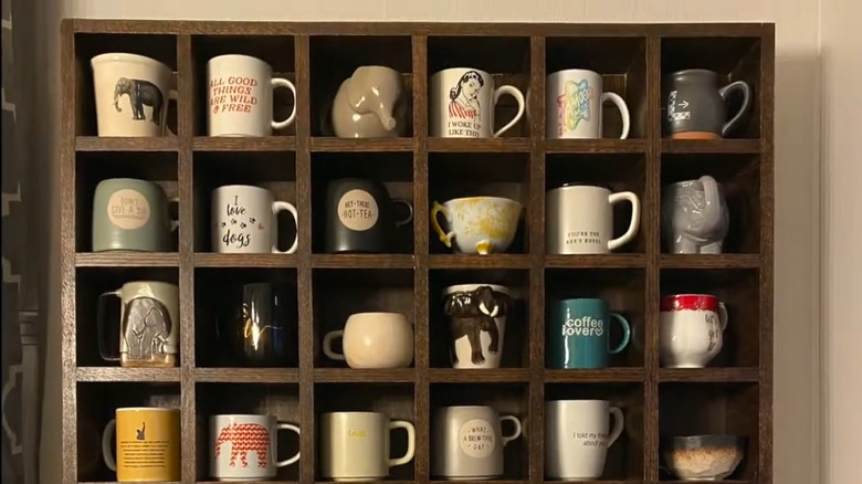 Each coffee mug sits in its own cubby in a display shelf made out of scrap wood.