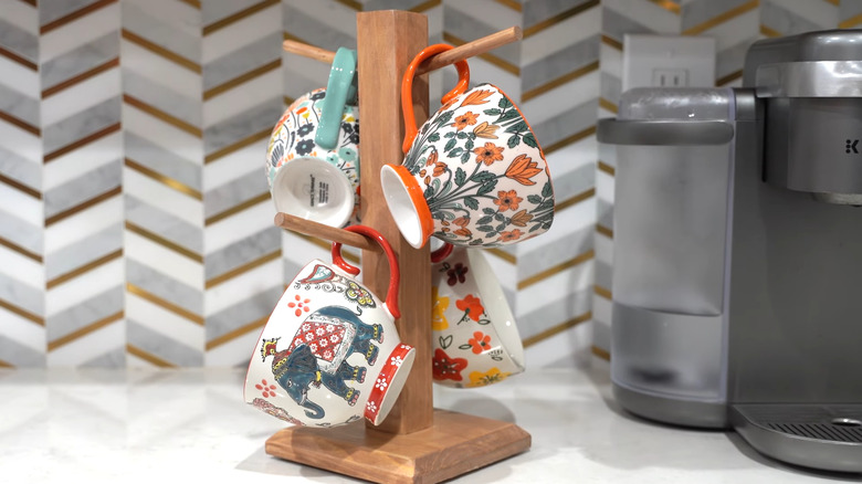 A DIY coffee mug stand made from dowels, a 2-by-2 pole, and a square wooden base.