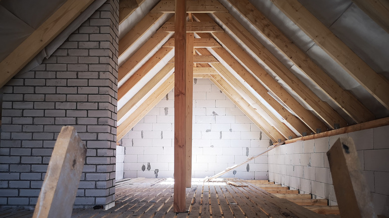 A brick wall and wood joists are shown in an unfinished attic