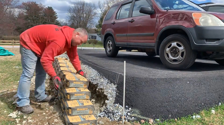 Man straightens concrete bags for the retaining wall he's building.