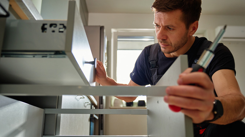 Someone adjusting the drawers on their kitchen cabinets.