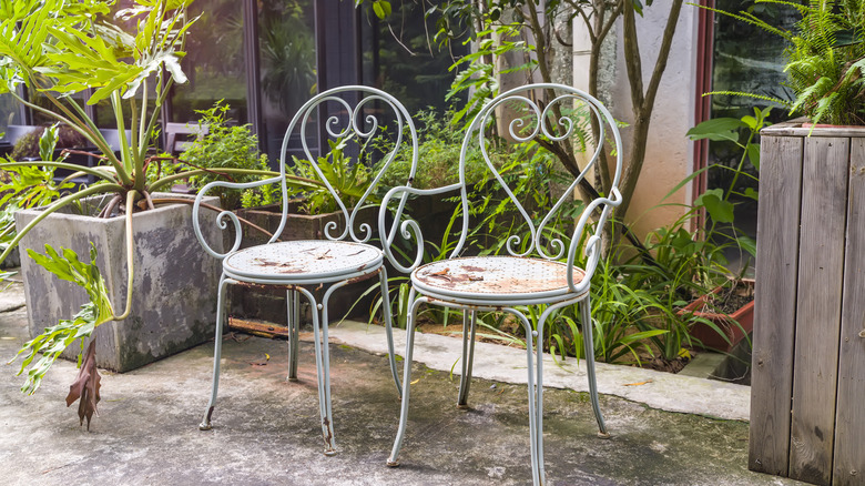 Two rusty chairs on dirty concrete patio