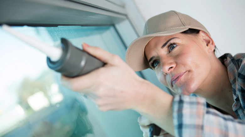 woman caulking a window