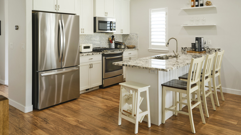 white kitchen with stainless steel refrigerator and white cabinets
