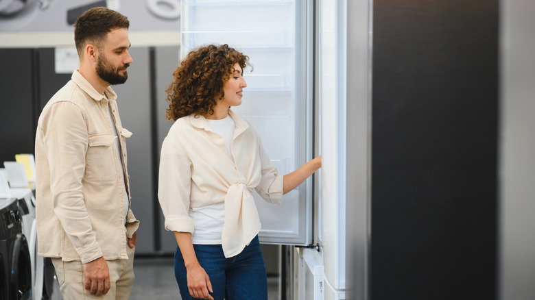 a couple choosing a new refrigerator in an appliance store