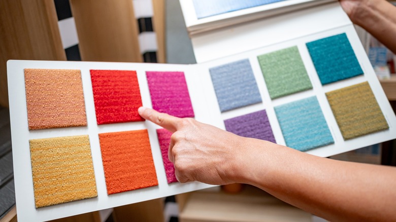 A hand pointing at colored rug samples