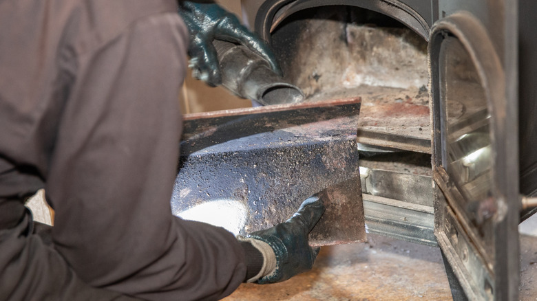 A man cleans a wood stove to help keep it safe.
