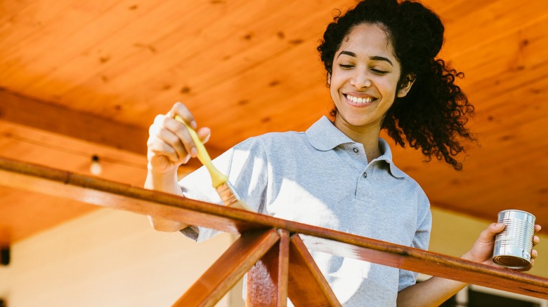 Woman painting deck railing 