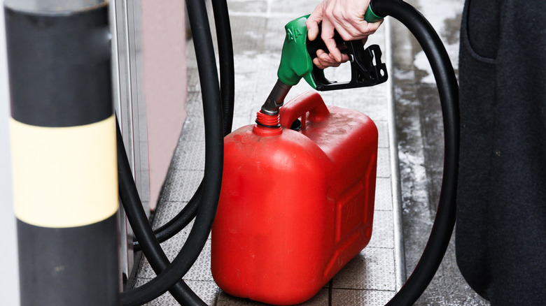 A person filling a gas can at a gas station