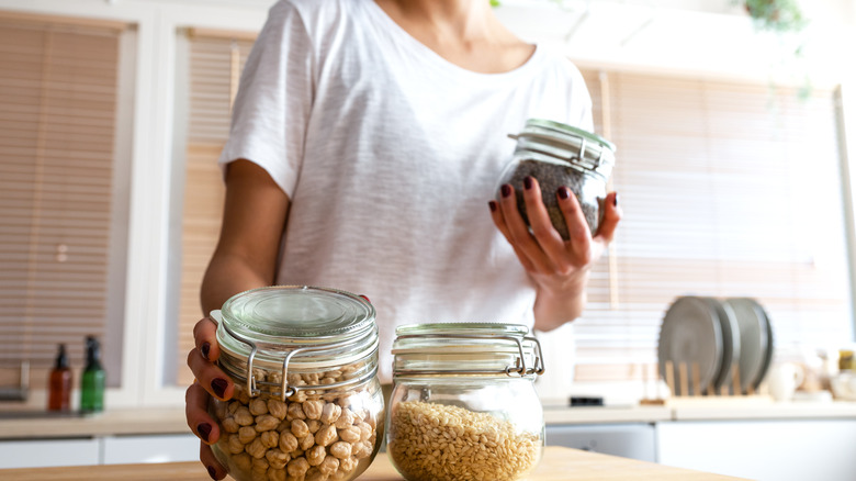 A woman organizing pantry items in clear jars in her kitchen