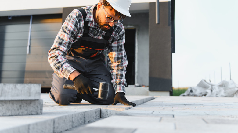 A person installs permeable paver stones for a patio