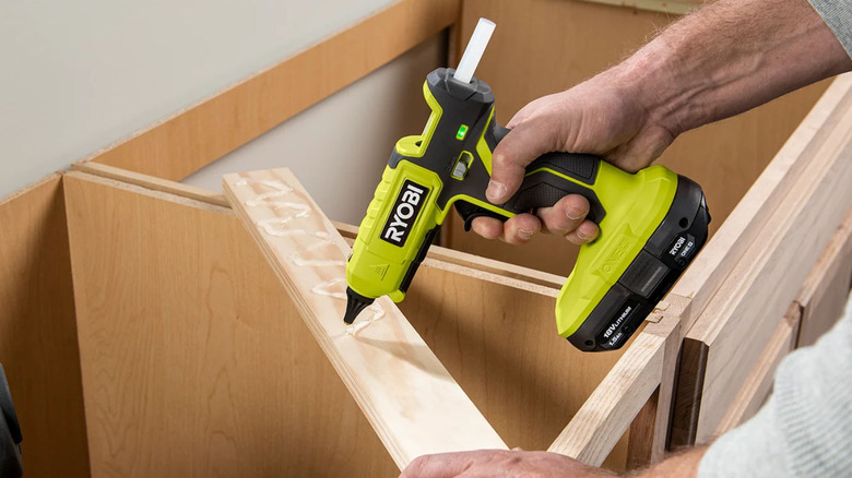 Someone using a Ryobi glue gun for cabinet woodworking
