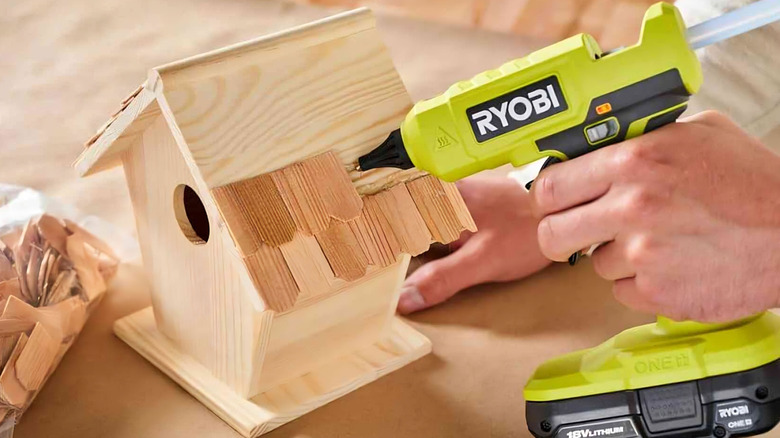 Someone using a Ryobi dual-temp glue gun to work on a birdhouse