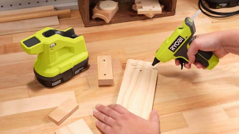 using the Ryobi compact glue gun and its base while working on a wood project