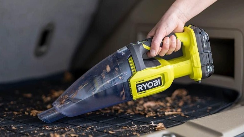 Person using a Ryobi hand vacuum to clean a car