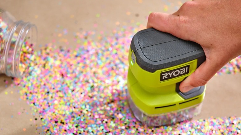 Person using a tiny desktop Ryobi hand vacuum