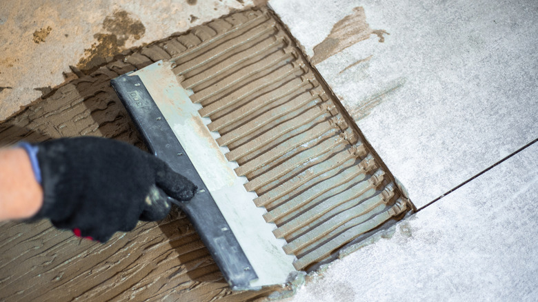Close up of large trowel, mortar, and tile