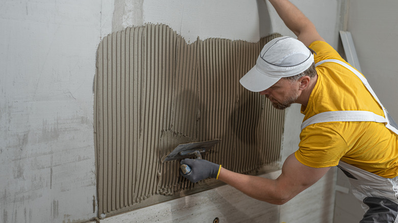 Worker laying down mortar for wall tiles with trowel