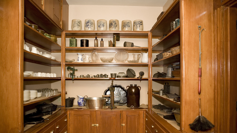 a large pantry with open wood shelves above and cabinets down below