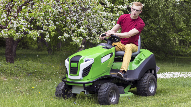 A young man driving a ride-on lawn mower