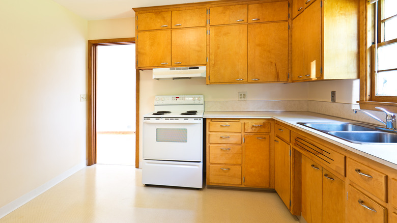 A kitchen with orange-toned wood cabinets and butter yellow walls and floor