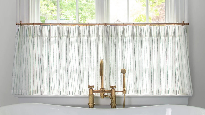 Cafe curtains hanging in front of a bathtub