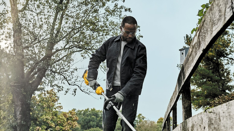 A man using DeWalt's cordless string trimmer