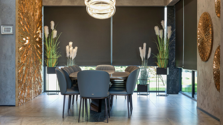 Large dining room with dark gray table, chairs, and window blinds lowered half-way, while large gold decor hangs on walls