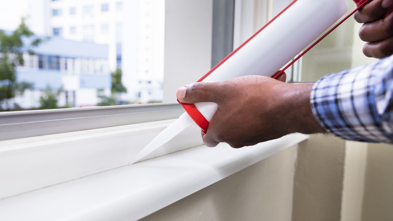 Person caulking a window