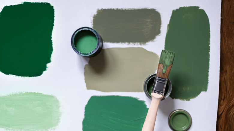 Samples of green paint colors with brush and can.