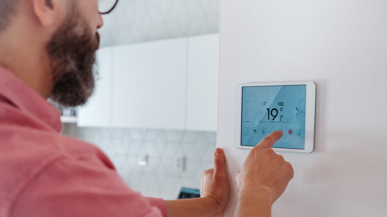 A man adjusts a smart thermostat