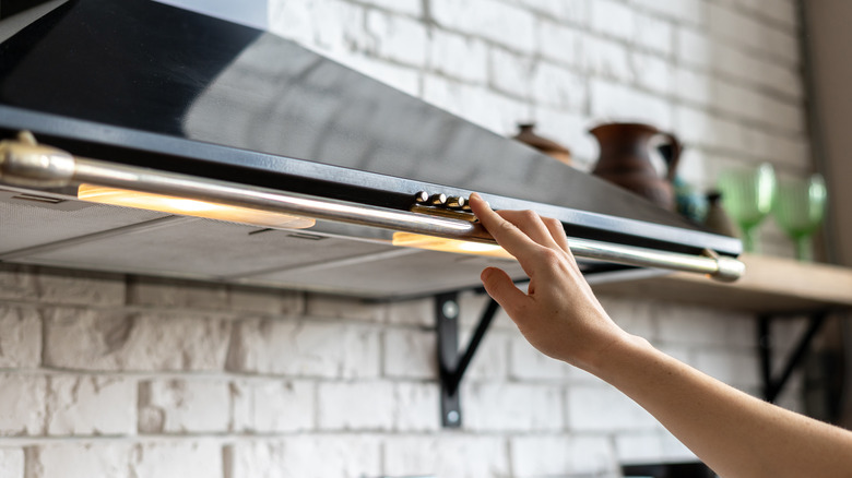Person pressing range hood button